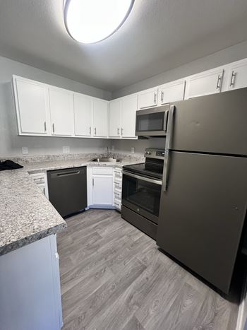 A kitchen with a refrigerator, oven, and microwave.